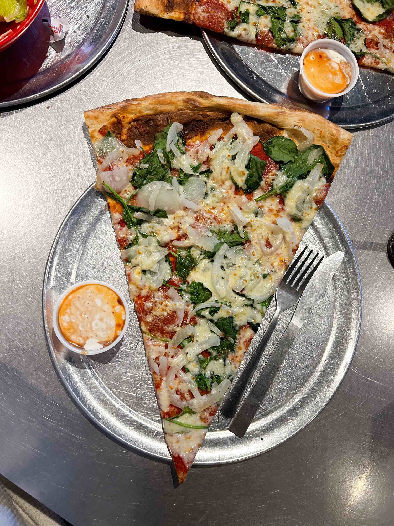 pizza slice with veggies on a metal table